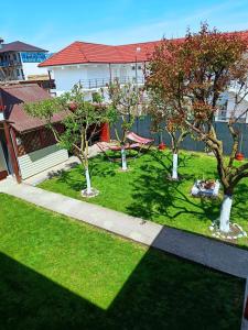 a lawn with trees in front of a building at Vila Aty & Michelle in Vama Veche