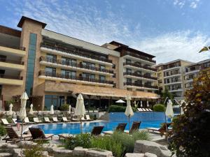 um hotel com uma piscina com cadeiras e guarda-sóis em Sea view apartament in Garden of Eden em Sveti Vlas