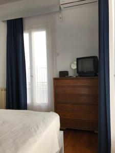 a bedroom with a bed and a tv on a dresser at VINTAGE HOUSE (4min from the port on foot) in Skopelos Town