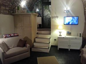 ein Wohnzimmer mit einer Treppe, einem Sofa und einem TV in der Unterkunft Casa Limonaia San Rocco in Limone sul Garda