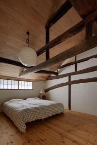 a bedroom with a bed and wooden ceilings with beams at Casa KitsuneAna The Satoyama experience in a Japanese-style modernized 100-year-old farmhouse in Akaiwa