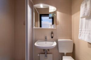 a bathroom with a sink and a toilet and a mirror at Hotel de La Poste in La Tzoumaz