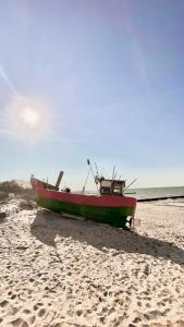 a red boat sitting on a sandy beach at BALTIC FAMILY Premium in Mielno
