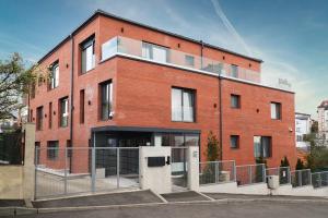 a red brick building with a fence in front of it at Panorama Deluxe Aparthotel in Cluj-Napoca