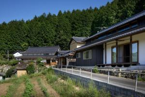 eine Reihe von Häusern auf einer Straße neben einem Wald in der Unterkunft Casa KitsuneAna The Satoyama experience in a Japanese-style modernized 100-year-old farmhouse in Akaiwa