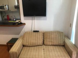 a couch in a living room with a flat screen tv at Apart hotel Champagnat in Belo Horizonte