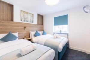 a hotel room with two beds and a window at The Chapter - Griffin House Hotel in London