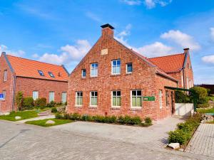 - un grand bâtiment en briques avec des fenêtres donnant sur une rue dans l'établissement Bummert am Hafen 3 Greetsiel, à Krummhörn