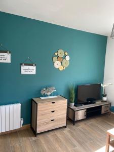 Elle comprend un salon doté d'un mur bleu et d'une télévision. dans l'établissement Le LH CENTRE VILLE, au Havre