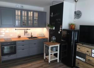 a kitchen with blue cabinets and a black refrigerator at Apartament 5 mórz in Sianozety