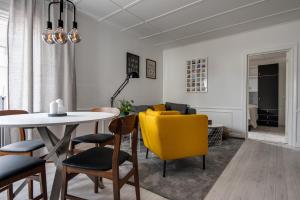 a living room with a dining room table and yellow chairs at Luxurious apartment for the modern executive in Luleå