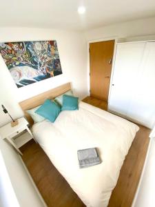 Un pequeño dormitorio con una gran cama blanca con almohadas azules en Camp Street Rooms, en Mánchester