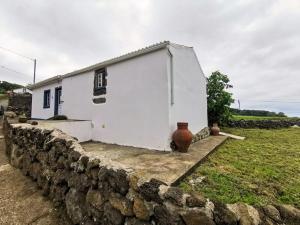 Biały dom za kamienną ścianą w obiekcie Casa da Emilie w Santa Cruz da Graciosa