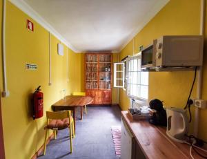 une cuisine avec une table et un mur jaune dans l'établissement Casa da Emilie, à Santa Cruz da Graciosa