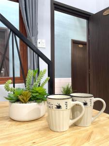 two coffee cups sitting on a table with plants at VANIA HOUSE - cozy studio near the airport in Ho Chi Minh City
