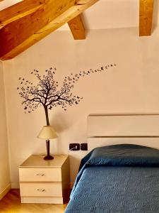 a bedroom with a tree with birds on the wall at Casa Gianna in Arco
