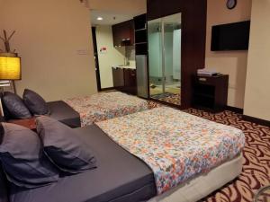 コタキナバルにあるStay In Kay Kay Hotel Suite at South China Sea Place Suiteのベッド2台と鏡が備わるホテルルームです。