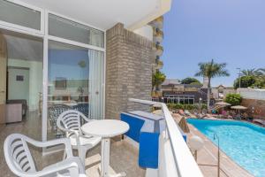 un balcón con mesa y sillas junto a una piscina en Hotel LIVVO Veril Playa en Playa del Ingles