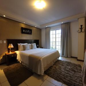 a bedroom with a large bed and a window at Pousada Cheverny - Fácil acesso ao centrinho e Baden Bar in Campos do Jordão