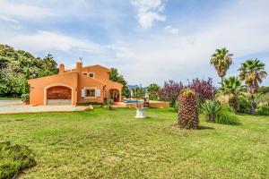 an orange house with a yard and a pool at Villa Zahara in Alcudia