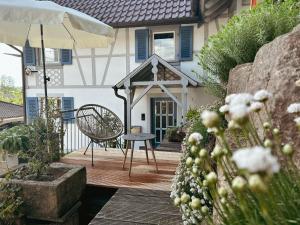 ein Haus mit einer Terrasse mit einem Stuhl und einem Sonnenschirm in der Unterkunft Ferienwohnung Silvi und Heinz Huber in Durbach
