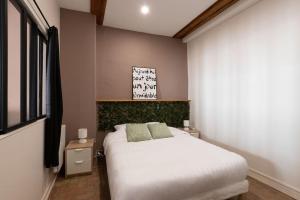 a bedroom with a white bed and a sign on the wall at Cabana & Le Petit Carnot - Centre-Ville in Tournus