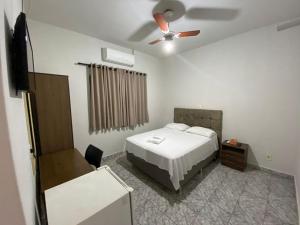 a bedroom with a bed and a ceiling fan at Hotel Sun City in Itápolis