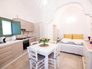 a white kitchen with a table and a bed at Dimora Nonna Lina in San Michele Salentino +11 photos