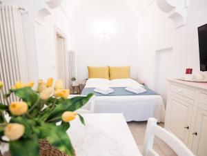 Cette chambre blanche comprend un lit et une table avec une plante. dans l'établissement Dimora Nonna Lina, à San Michele Salentino