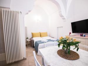 ein Wohnzimmer mit einem Tisch, einem Bett und einem TV in der Unterkunft Dimora Nonna Lina in San Michele Salentino