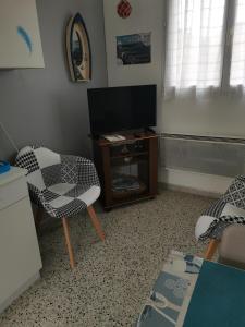 ein Wohnzimmer mit einem TV, einem Tisch und Stühlen in der Unterkunft Gite du Dien in Ponthoile