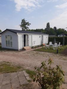 ein weißes Haus mit 2 Stühlen und einer Terrasse in der Unterkunft Chalet Olm 22 in Zoerte