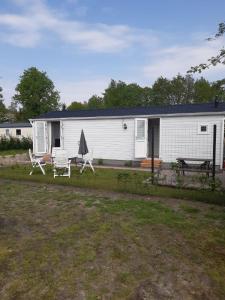 a white house with two chairs and an umbrella at Chalet Olm 22 in Zoerte