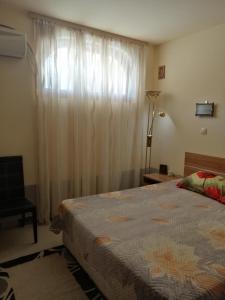 a bedroom with a bed and a window with curtains at Cozopol Budjaka in Sozopol