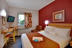 una camera d'albergo con un grande letto e una scrivania di Road Lodge JNB Airport a Johannesburg