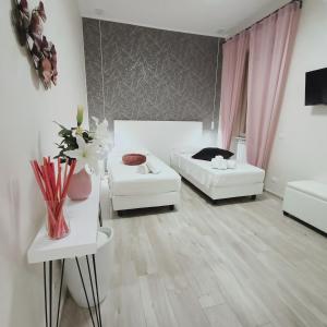 una sala de estar con muebles blancos y cortinas rosas. en Come a Casa Pretty Apartment en Lido di Ostia