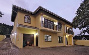 a large yellow house with windows and a driveway at Tuksumduin in Ballito