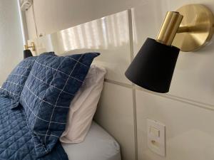 a bed with a blue pillow and a lamp at Hotel APART Zuccolotto 303 in Aracruz