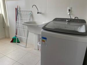 a kitchen with a sink and a washing machine at Hotel APART Zuccolotto 303 in Aracruz