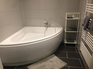 een wit bad in een badkamer met zwarte tegels bij City Appartment Krefeld - 20 km DUS Airport/Messe in Krefeld