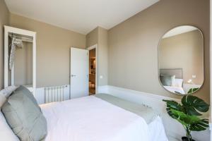 sypialnia z białym łóżkiem i lustrem w obiekcie Apartamento Embajadores XVII w Madrycie +29 zdjęć