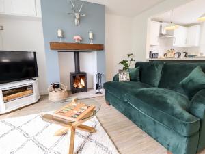 a living room with a green couch and a fireplace at 6 Hillside Cottages in Gainsborough
