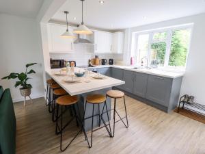 a kitchen with a large white island with stools at 6 Hillside Cottages in Gainsborough