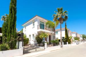 a white house with palm trees on a street at Villa Natalie in Protaras
