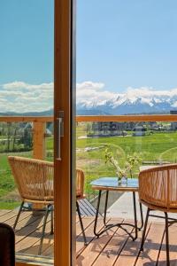 d'une terrasse avec une table, des chaises et des montagnes. dans l'établissement Białka Residence Ski - 100m do Termy Bania, à Białka Tatrzańska