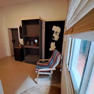 Maluda B&B في تايمالي: كرسي في غرفة مع لوحة رجل