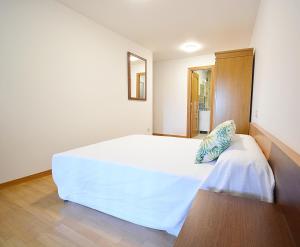 a bedroom with a large white bed and a mirror at Adosado I en Vilanova de Arousa in Villanueva de Arosa