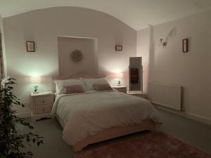 - une chambre avec un lit et 2 tables de nuit avec des lampes dans l'établissement Cupcake Cottage: Quintessential Cotswold Cottage, à Nailsworth