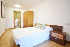 a bedroom with a white bed and a wooden cabinet at Adosado I en Vilanova de Arousa in Villanueva de Arosa