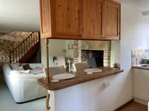 une cuisine avec un comptoir et un salon avec un canapé dans l'établissement Cupcake Cottage: Quintessential Cotswold Cottage, à Nailsworth